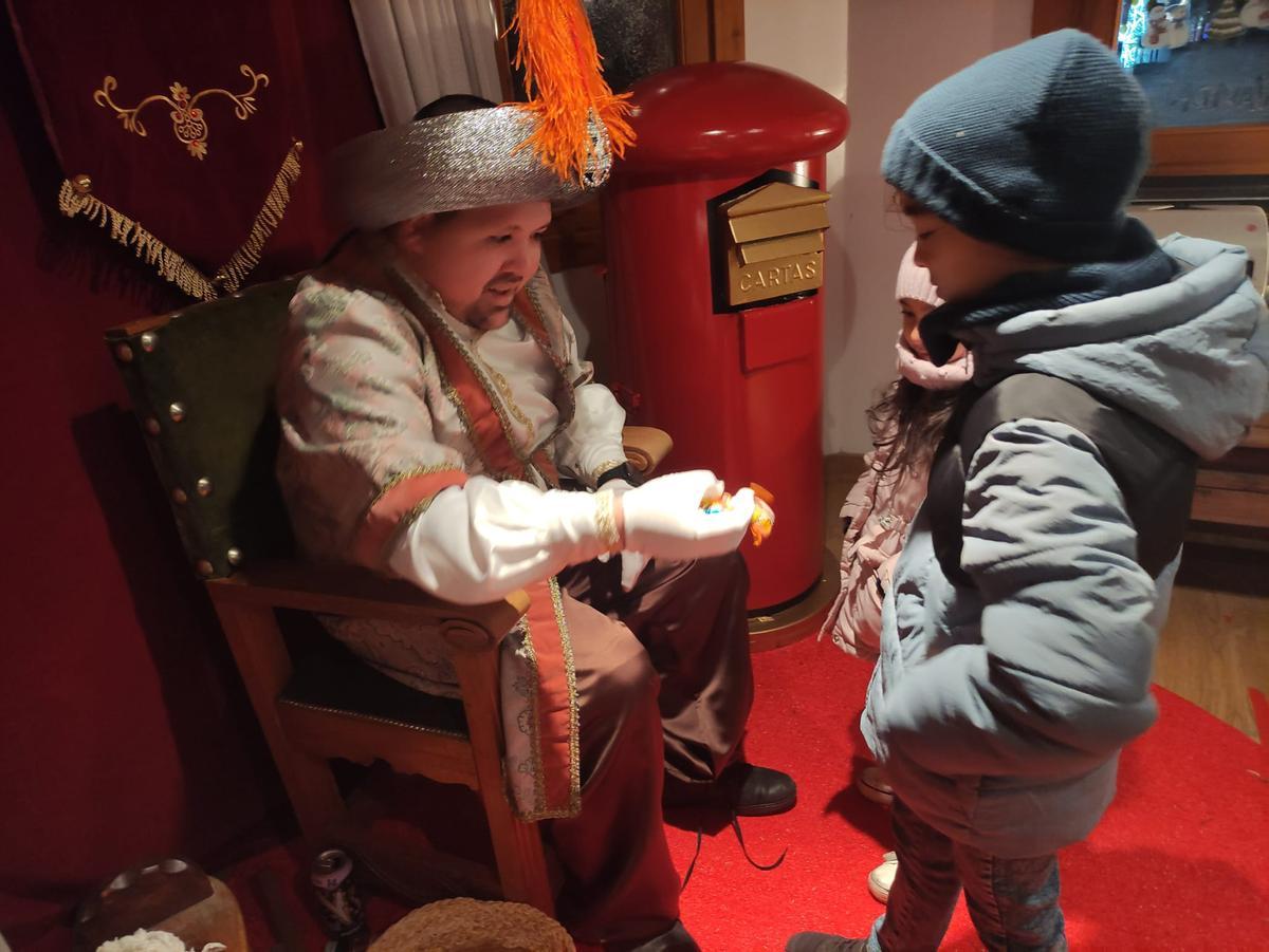 El paje real entrega caramelos a dos niños.