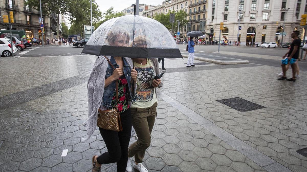 Dos mujeres se protegen de la lluvia en Barcelona.