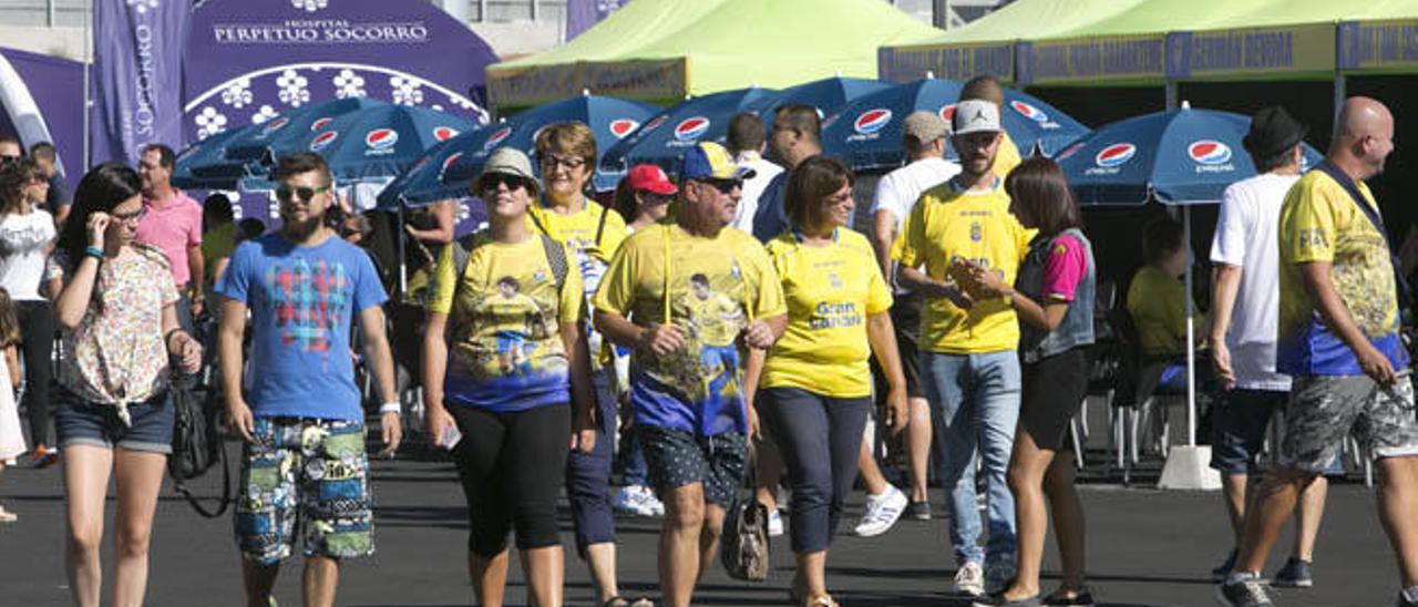 Un grupo de aficionados amarillos vislumbra los puestos de la Fan Zone.