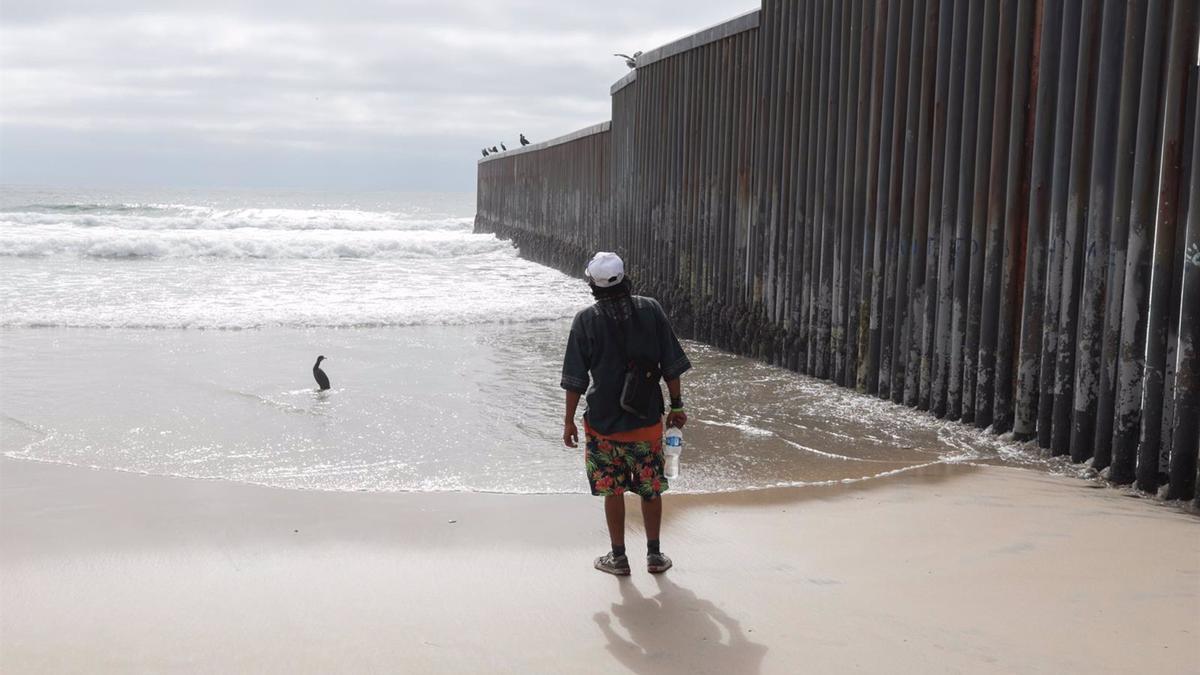 Migrante en el muro de separación con EEUU