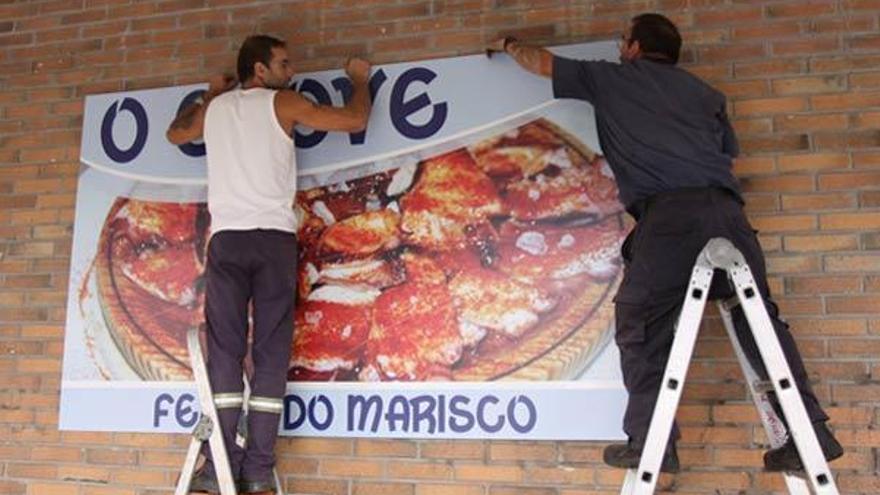 Colocación del cartel que anuncia la presente edición de la Festa do Marisco de O Grove.  // Muñiz