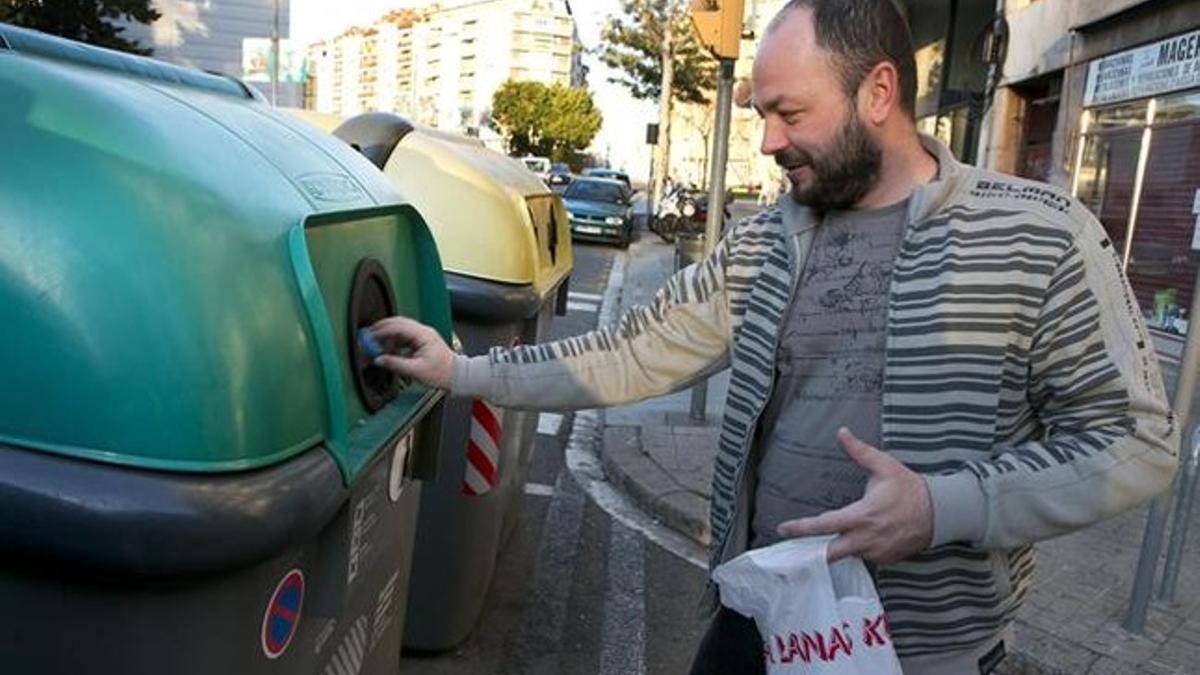 Un usuario deposita envases de vidrio en un contenedor en Barcelona.