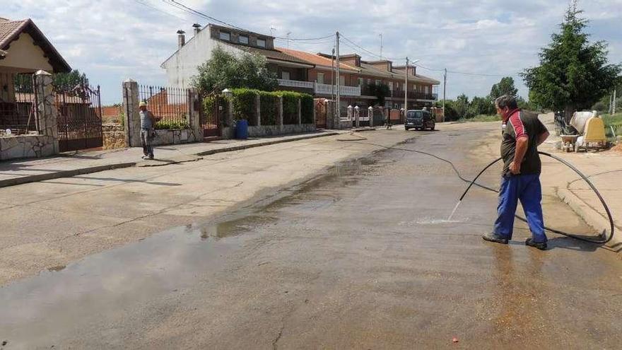 Un vecino de Quiruelas limpia la calzada tras rebosar las aguas fecales y pluviales de los registros de saneamiento por la tormenta.