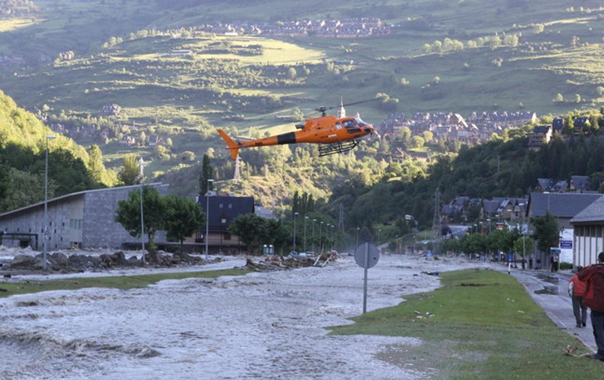 Un helicòpter sobrevola la Garona, amb el cabal més baix, a Viella.