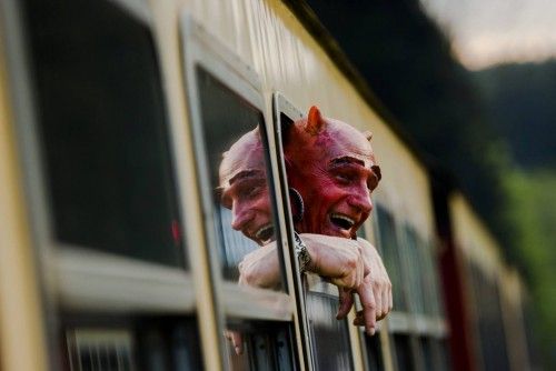 Man with devil make-up looks out of HSB light railway carriage as he travels through the Harz mountains
