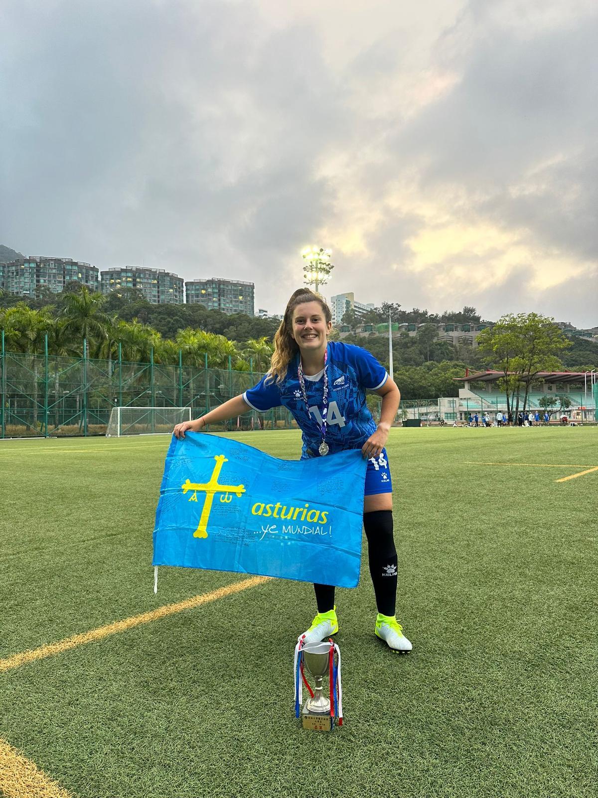 Laura Díaz, en Hong Kong, con la bandera de Asturias y el trofeo de subcampeonas de la liga universitaria honkonesa.