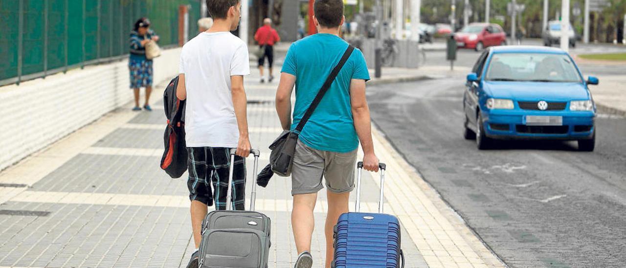 Jóvenes ilicitanos con maletas en dirección a la estación de tren de Renfe.