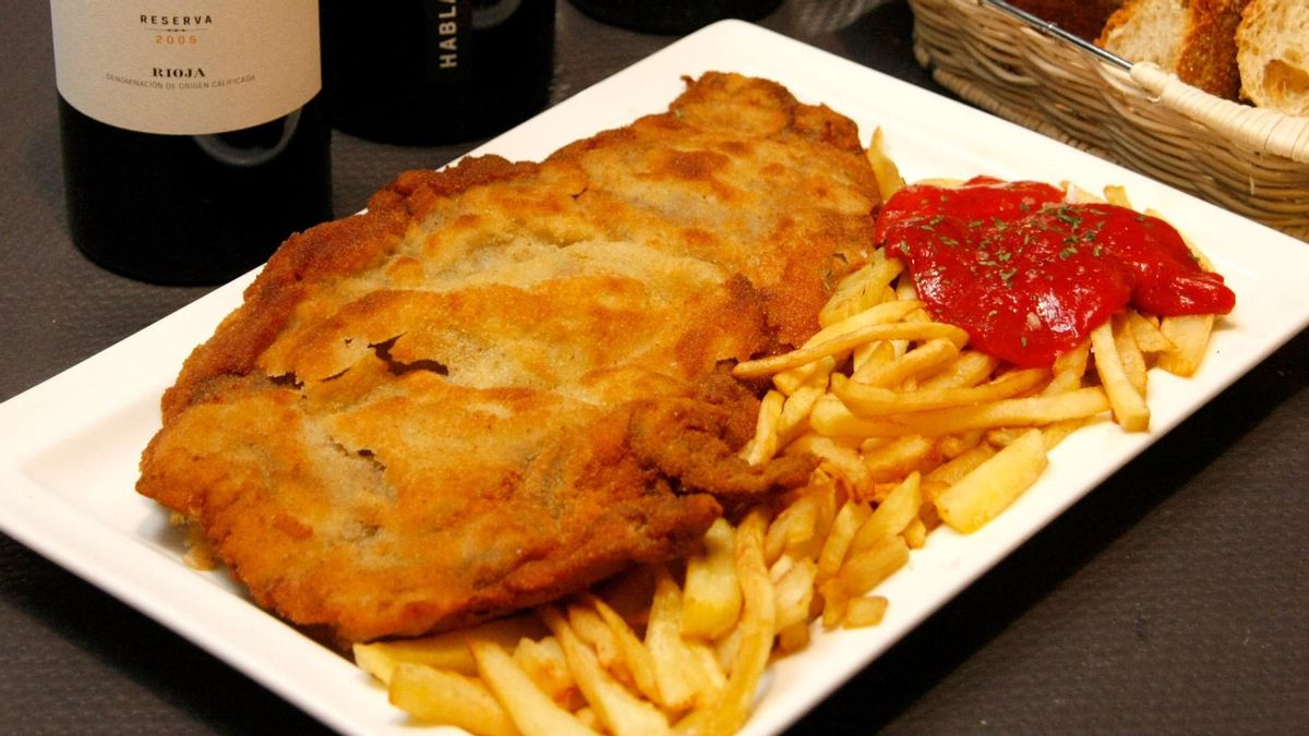 Un cachopo con patatas fritas y pimientos rojos asados