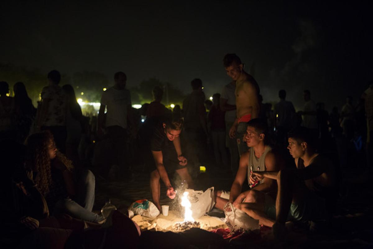 Un grup de joves fan una foguera a la platja de la Nova Icària.