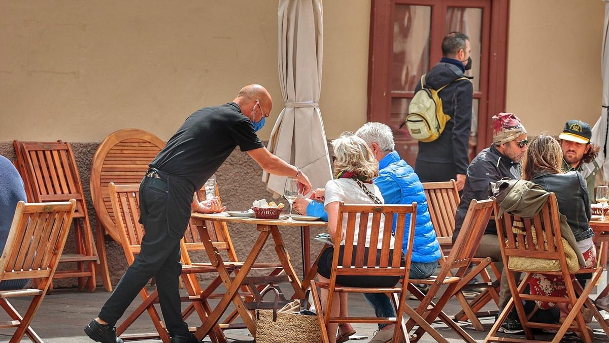 Un camarero atiende a unos clientes en una terraza de un bar lagunero.