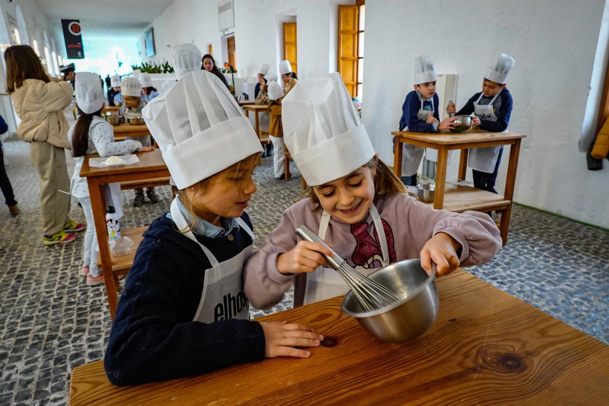 Dos niñas baten la crema de queso que luego echan por encima de las perrunillas.