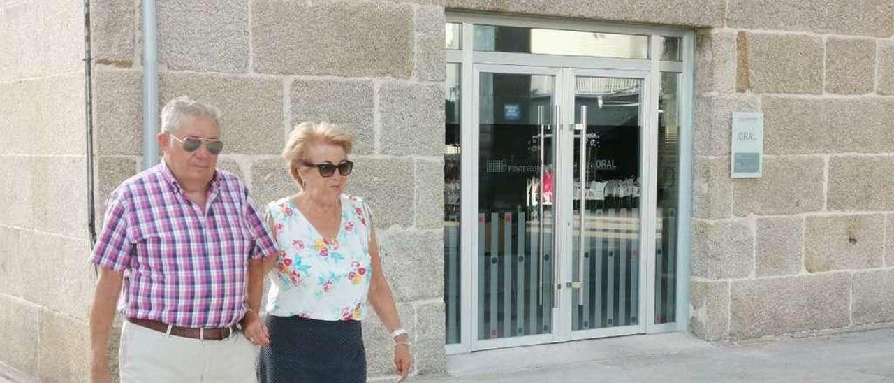 Una pareja, paseando delante de la oficina del ORAL en Cangas. / Santos Álvarez