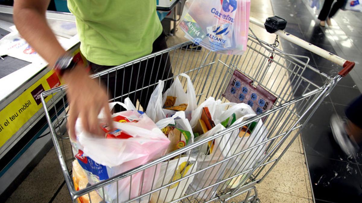 Un hombre, con el carro de la compra, en un supermercado.