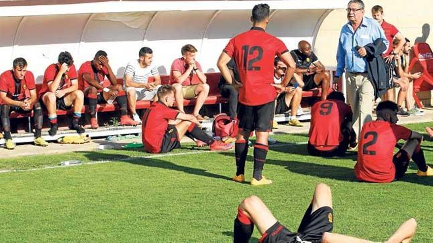 El directivo Paco Galmés consuela a los jugadores del Mallorca B, rotos tras conocer su descenso a Tercera División.