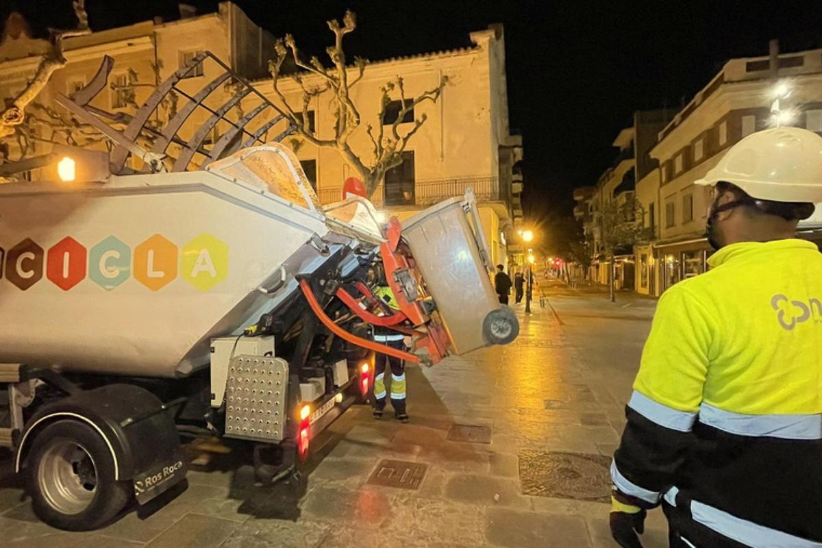 Dos treballadors de l'empresa de recollida d'escombraries de Blanes s'emporten un contenidor d'orgànica.