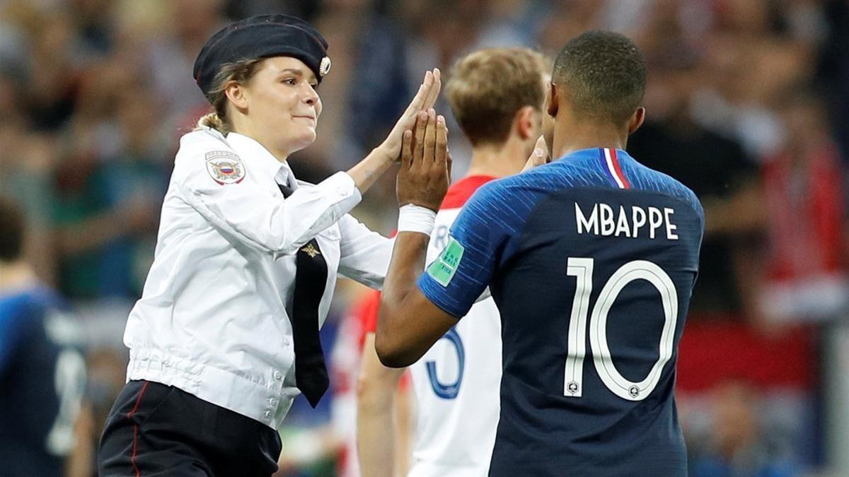 Una miembro de la banda Pussy Riot chocandole la mano a Kylian Mbappé