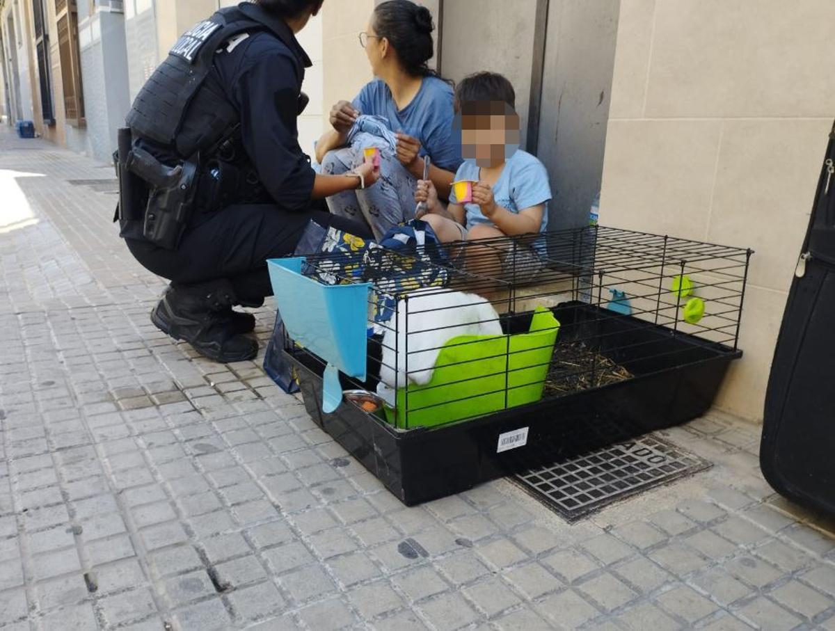 Una policía local atiende a la mujer y al niño desalojados por el incendio.