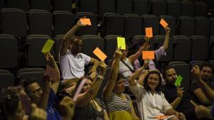 El público vota con cartulinas a mano alzada durante el espectáculo.