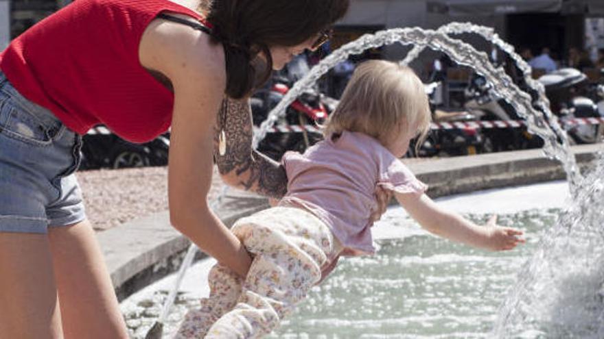 Una mare refresca a la seva filla davant la calor.