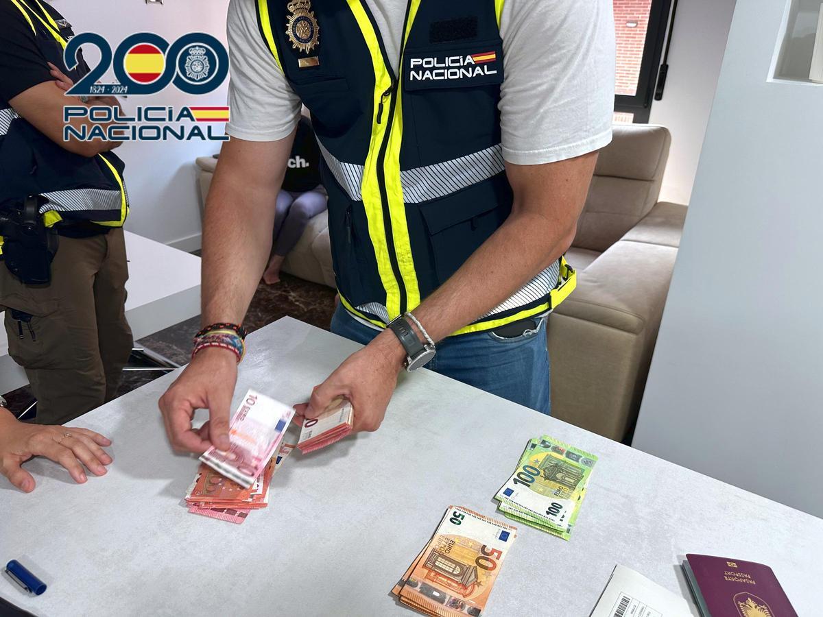 Un policía cuenta el dinero intervenido en un registro.