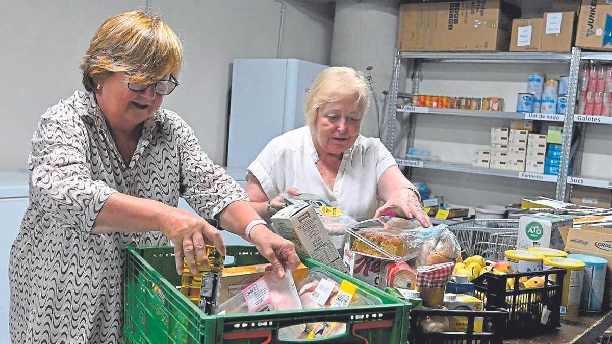 Dos voluntarias preparan lotes de alimentos para su distribución a través de entidades sociales en un banco de alimentos.
