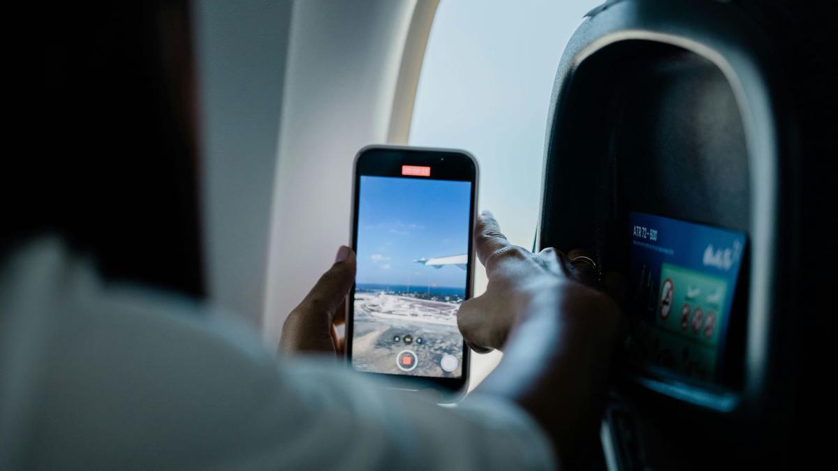 Una persona graba un vídeo con un Iphone en un avión.