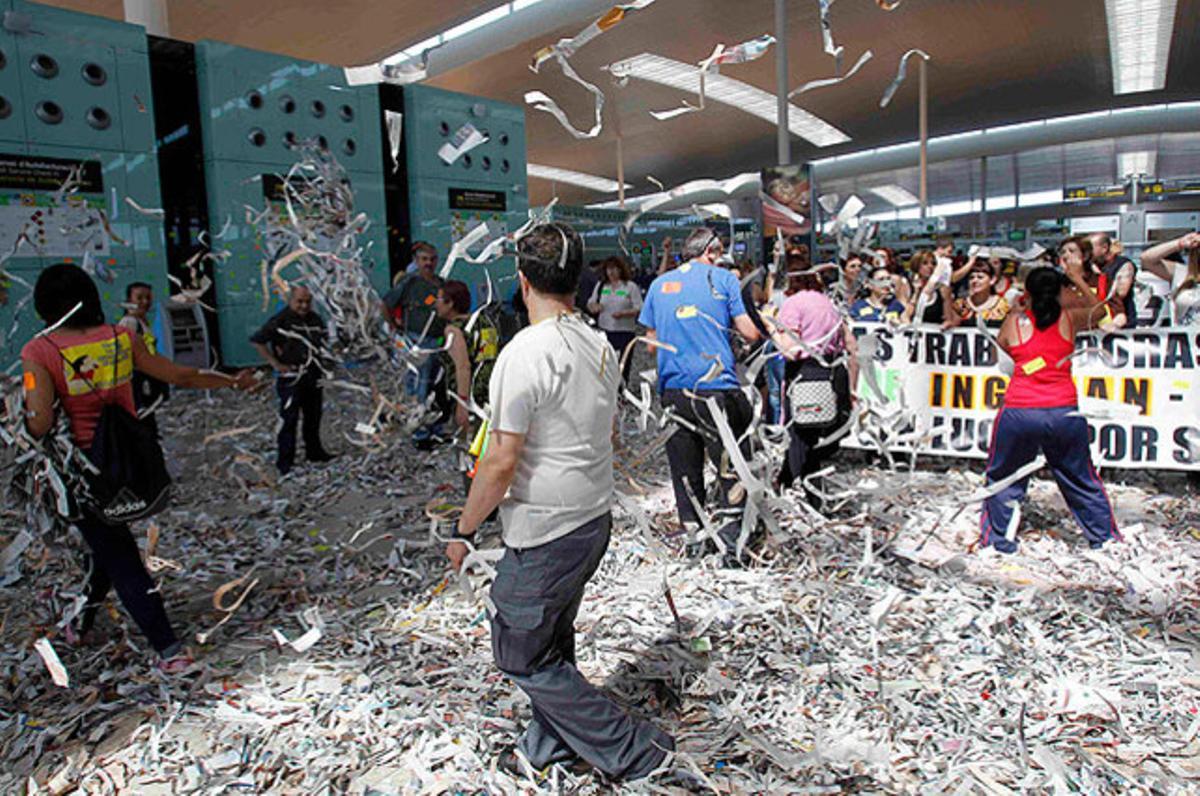 Treballadors del servei de neteja tiren trossos de paper a  de la terminal T-1 de l’aeroport del Prat, durant la vaga convocada pels sindicats per exigir millores en la seva situació laboral.