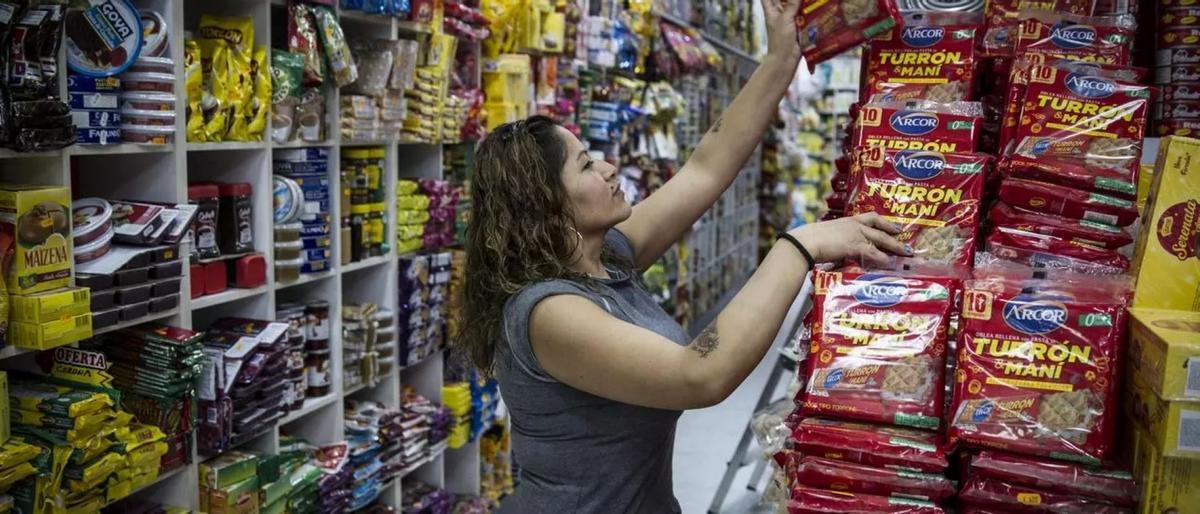Una trabajadora repone productos en un comercio, en una imagen que ilustra el peso del empleo extranjero en actividades de venta y servicios.