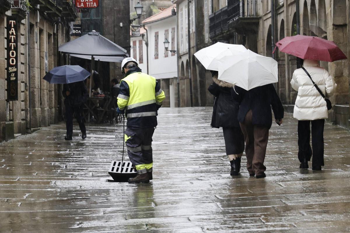 Un operario revisa las alcantarillas en Santiago en una jornada de lluvia