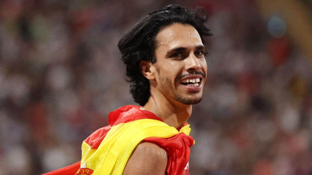 Mohamed Katir sonríe durante su vuelta de honor con la bandera española colgada de su cuello. | LUKAS BARTH/REUTERS