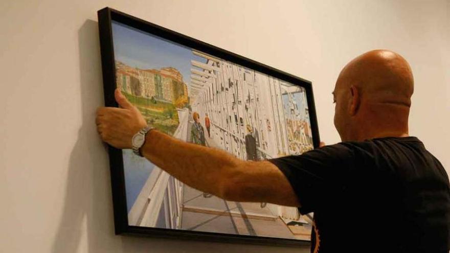 Ángel Almeida cuelga uno de los cuadros de la muestra.