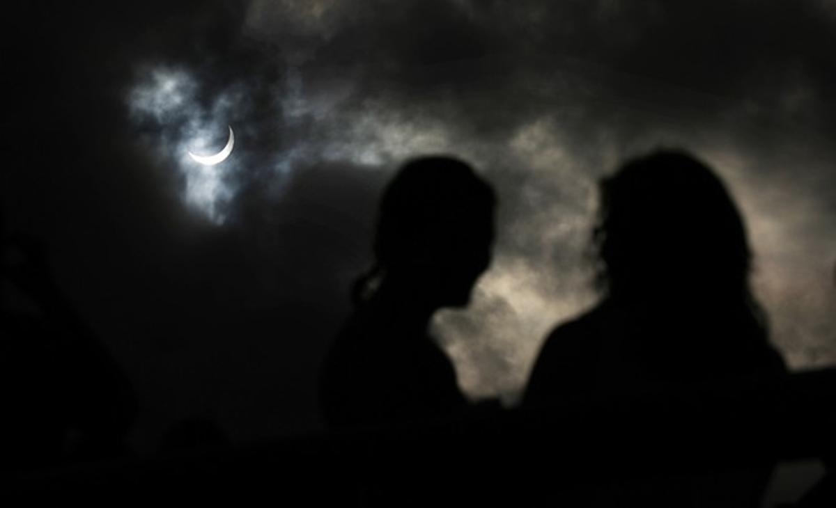 Un grup de persones observen com la Lluna passa per davant del Sol, a Cairns.