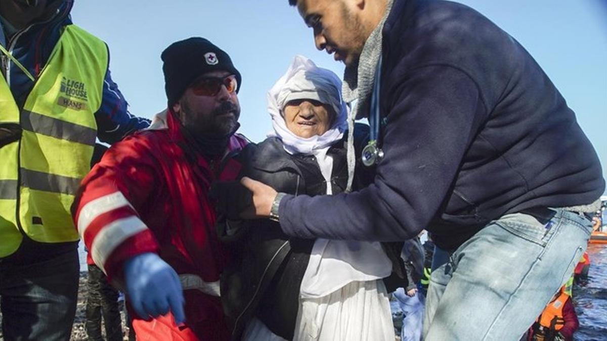 Voluntarios ayudan a una mujer anciana de Afganistán tras desembarcar con otros refugiados en Skala Sykaminias, en Lesbos, este miércoles.