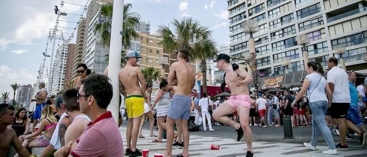 Dos vecinos cruzan el paseo de Levante a plena luz del dia atestado de turistas en plena juerga.