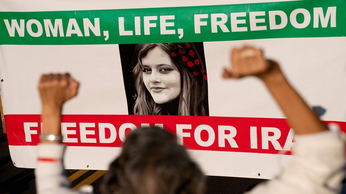 Una mujer protesta frente a un cartel de Masha Amini.