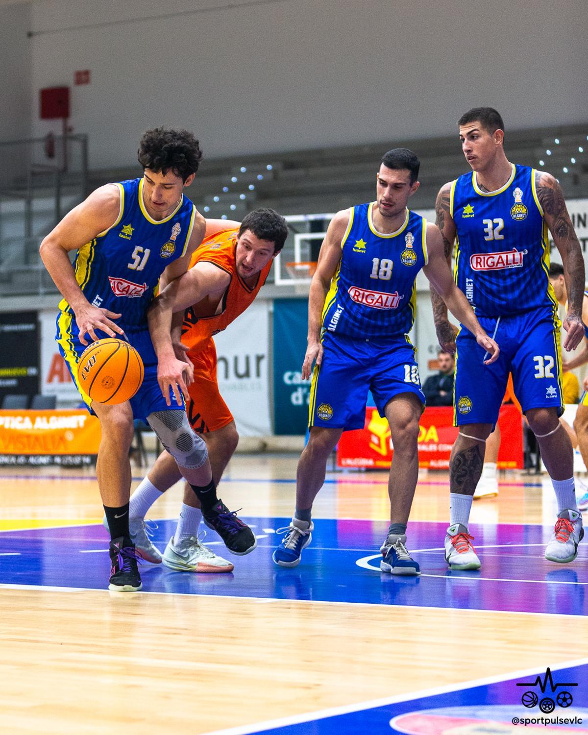 Tres jugadores del CB Alginet rodean a un contrario en la disputa por un balón.