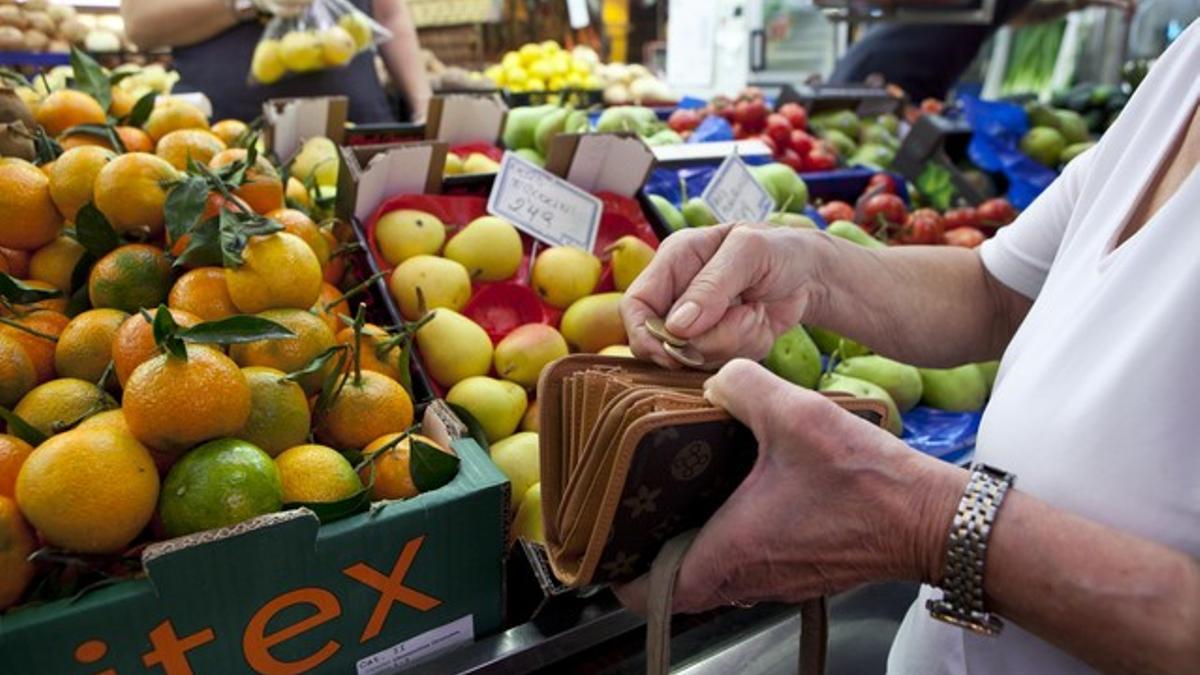 Una mujer, ante una parada de fruta y verdura en el mercado de Collblanc, en Barcelona.