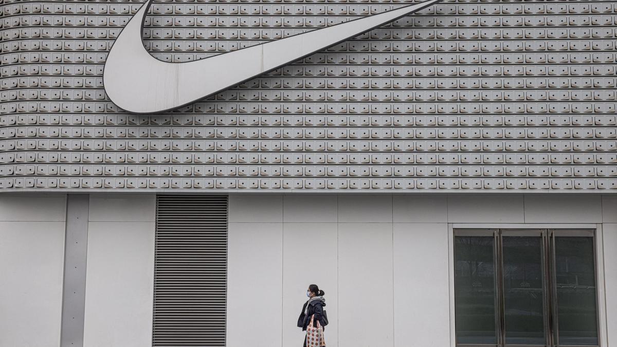 Una mujer pasan frente a una tienda Nike en Pekín.