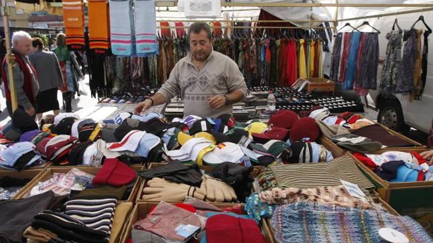 Un tendero ordena sus productos en su puesto del mercadillo de Huelin.