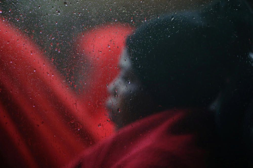 A migrant woman sits in a bus after disembarking ...