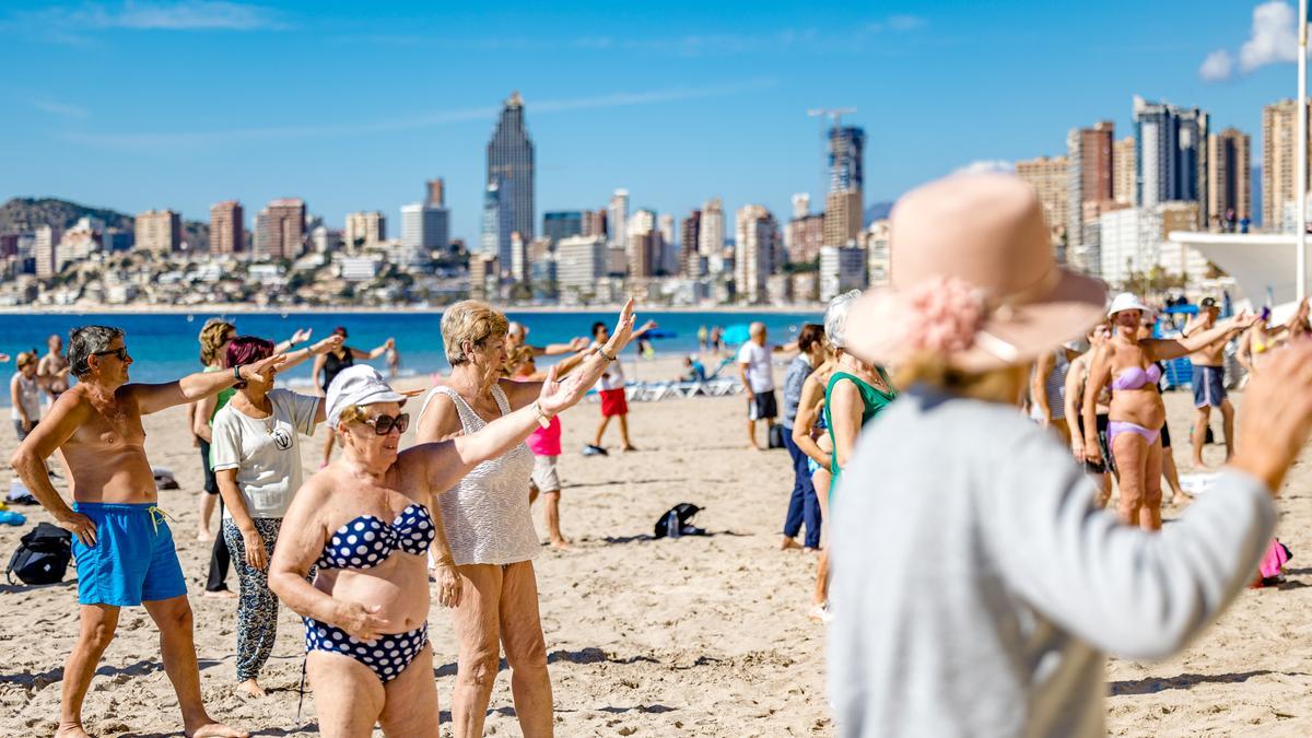 Personas de la tercera edad haciendo gimnasia en la playa de Benidorm, destino preferido por los jubilados que viajan en el Imserso.