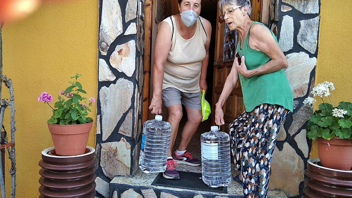 Una trabajadora municipal reparte agua en un domicilio de Junquera de Tera ayer por la tarde.