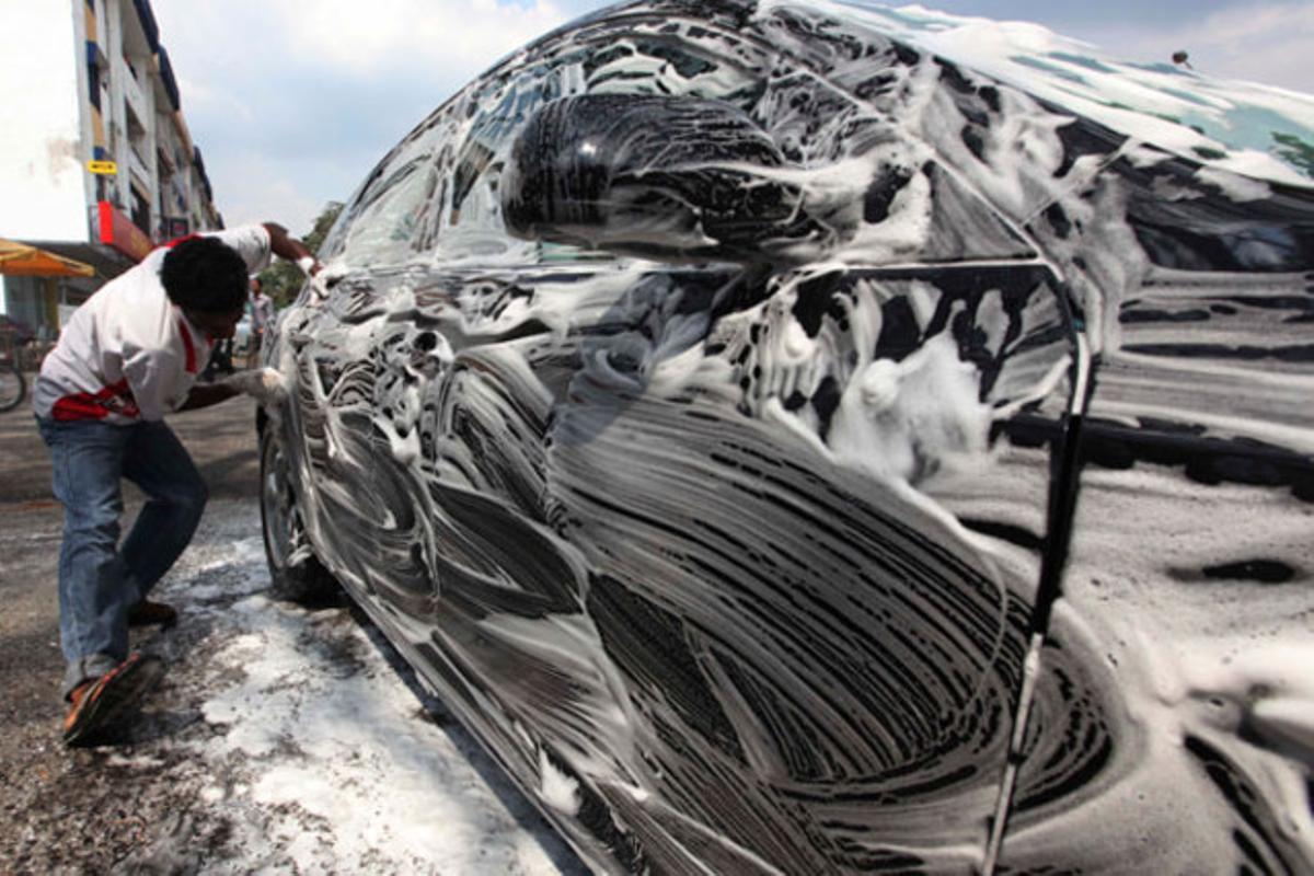 Un treballador neteja un cotxe en un suburbi de Kuala Lumpur (Malàisia).