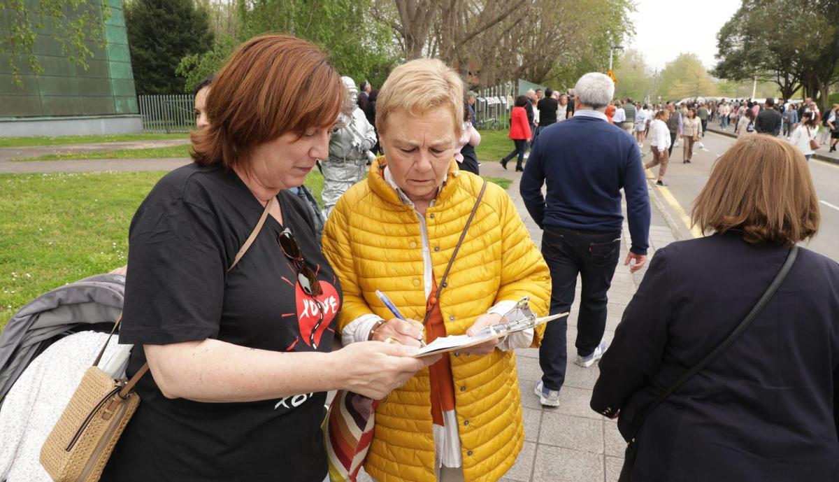 La presidenta de la Unión de Comerciantes del Principado de Asturias, Sara Menéndez, firmando en la mesa que colocó a la entrada del rastro la federación vecinal.