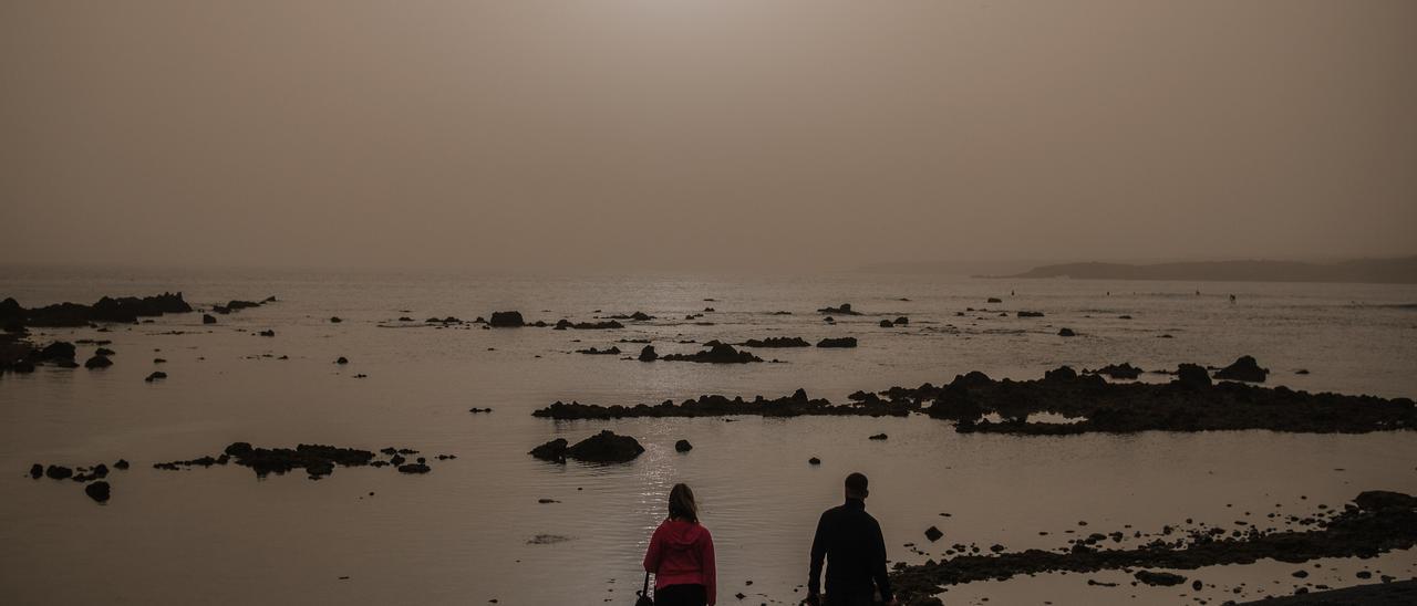 Una pareja en una playa del sur de Tenerife durante el episodio de calima de enero de 2022