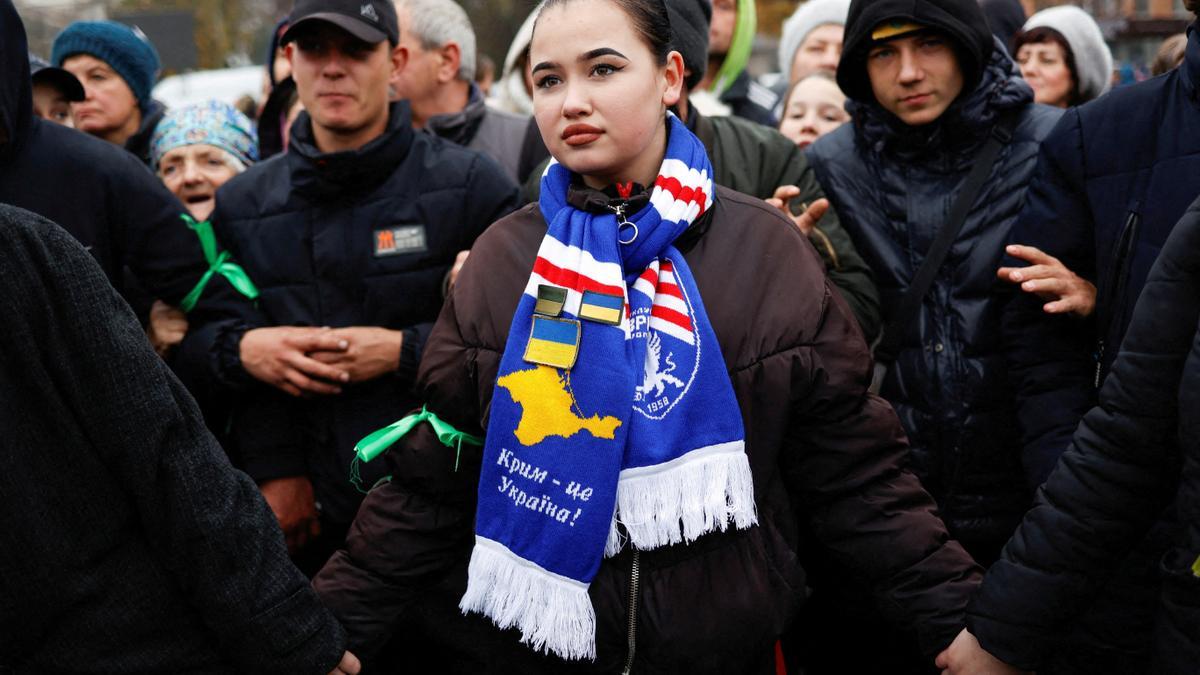 Una mujer lleva una bufanda con el lema &quot;Crimea es Ucrania&quot; impreso, mientras la gente espera en la cola para la distribución de alimentos después de la retirada de Rusia de Kherson, Ucrania, 17 de noviembre de 2022.