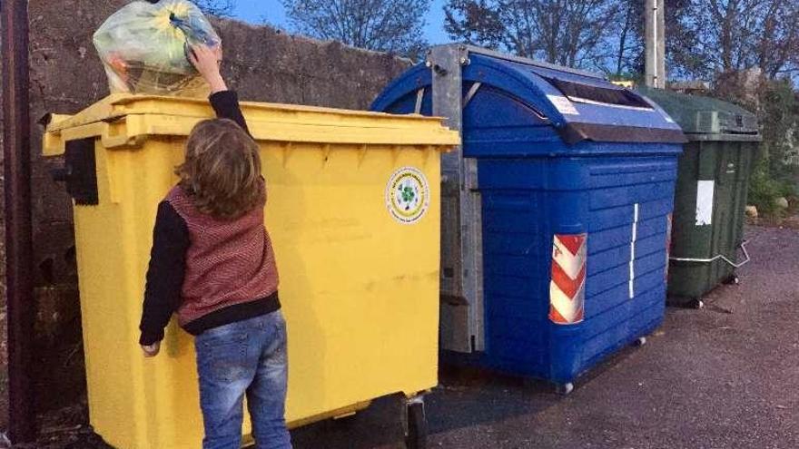 Un niño deposita una bolsa en un contenedor en Tomiño. // D.P.