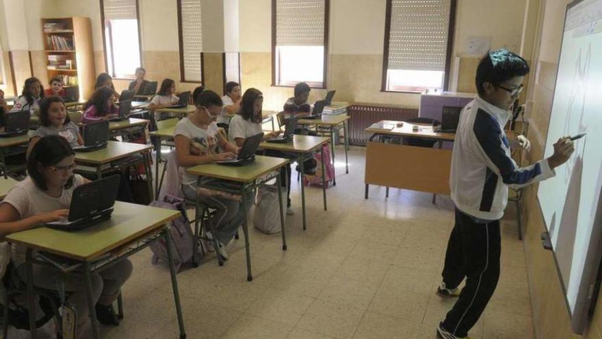 Alumnos de un centro gallego en una clase con ordenadores y pizarra digital.