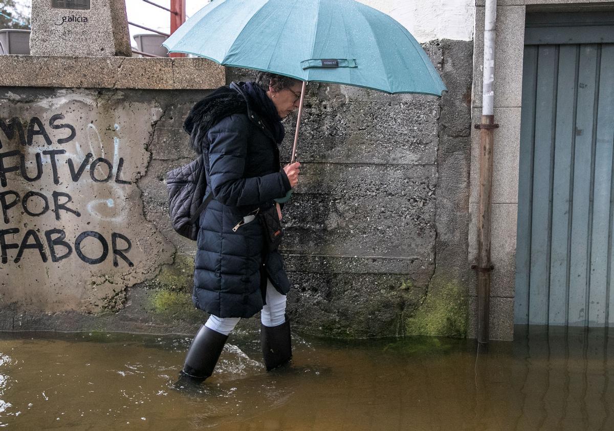 Una mujer camina por una zona inundada del barrio del Puente Romano en Lugo. En la capital de provincia preocupa la crecida del nivel del río Miño, que ya ha superado los cuatro metros de altura, que está por encima del umbral de alerta.