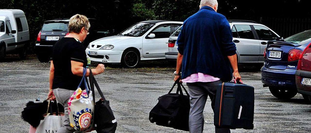 Dos turistas se dirigen a su coche en la explanada de un hotel de O Salnés.